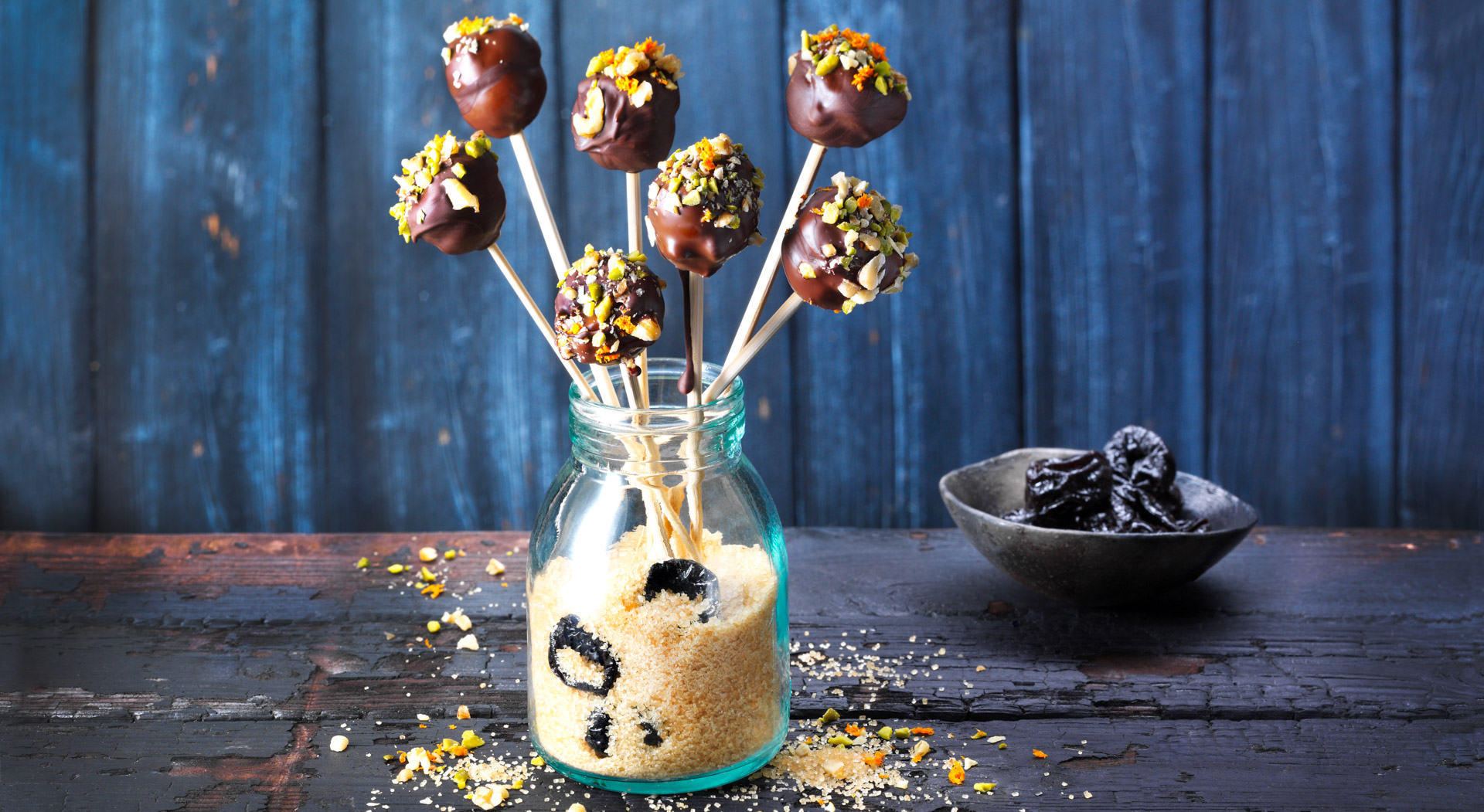 Marzipan, orange, and a trio of nuts form the filling for these prune and and chocolate lollipops. For coating the lollipops, source couverture chocolate, which has a higher percentage of cocoa butter and is ideal for tempering and dipping.